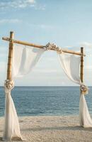 A bamboo arch with white fabric draped over it photo
