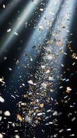 A shower of glittering confetti, highlighted by piercing light rays that create sharp contrasts between the bright pieces and the dark background photo