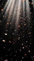 Abstract image of falling confetti illuminated by soft, scattered light rays, creating a magical and ethereal atmosphere over a black background photo