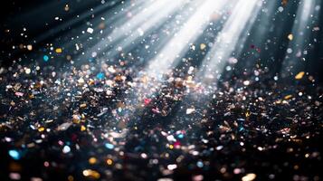 A shower of glittering confetti, highlighted by piercing light rays that create sharp contrasts between the bright pieces and the dark background photo