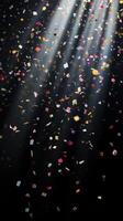 Abstract image of falling confetti illuminated by soft, scattered light rays, creating a magical and ethereal atmosphere over a black background photo