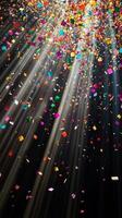 Colorful confetti suspended mid-air, with beams of light fanning out and illuminating the particles as they fall against a black void photo