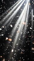 Dynamic image of swirling confetti, caught in beams of white light, with the dark background enhancing the brightness and movement of the scene photo