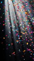 Multicolored confetti raining down against a black backdrop, with dramatic light rays streaming through the scene, casting shadows and reflections photo
