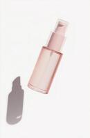 A sleek, plain cosmetic pump bottle floating horizontally in mid-air, casting a delicate shadow on a white background photo