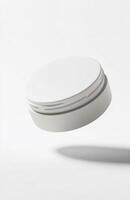 A plain, round cosmetic jar floating at an angle in mid-air, with smooth lighting and subtle reflections on its surface, isolated on white photo