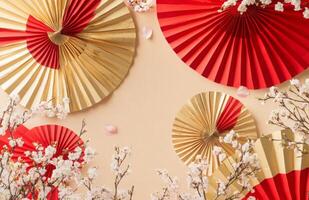 Red and gold paper fans on a wall with cherry blossoms photo