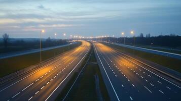 A quiet highway at dusk, illuminated by streetlights, with a soft glow on the asphalt photo