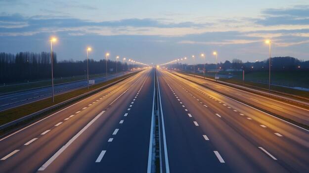 A quiet highway at dusk, illuminated by streetlights, with a soft glow on the asphalt photo