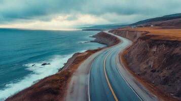Empty coastal highway hugging the shoreline, with the ocean to one side and cliffs on the other photo