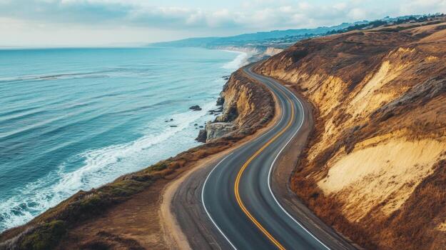 Empty coastal highway hugging the shoreline, with the ocean to one side and cliffs on the other photo