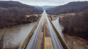 An expansive highway bridge crossing over a river, surrounded by nature and no signs of human activity photo