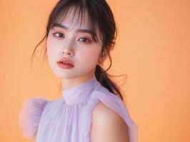 Close-up of a young Asian woman in a pale lavender dress, her expression calm, against a pastel orange background with copy space photo