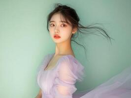 Beauty shot of a young Asian woman wearing a pastel lavender dress, posing against a soft pastel green background with ample copy space photo