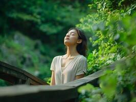 A woman standing on a wooden bridge in nature, eyes closed, breathing deeply, surrounded by greenery with copy space above and around her photo
