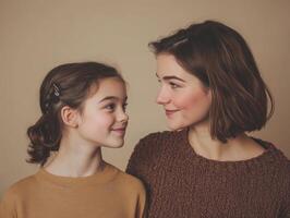 A mother and daughter or close friends, one young and the other mature, standing together, looking at each other with smiles, in a simple backdrop photo