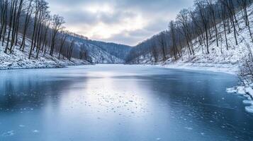 A serene frozen lake surrounded by snow-covered hills and bare trees, with soft light reflecting off the ice photo