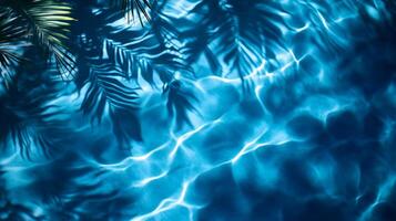 Abstract aqua wave patterns with blurred tropical leaf shadows swaying on a deep blue water texture photo