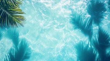 Abstract top view of turquoise waves with sharp tropical leaf shadows dancing on the blue background photo