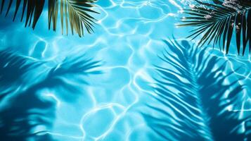 Bright blue pool water with soft ripples, highlighted by tropical leaves' shadows gently swaying on the surface photo