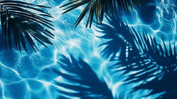Bright blue pool water with gentle waves and bold tropical leaves' shadows cast across the surface photo