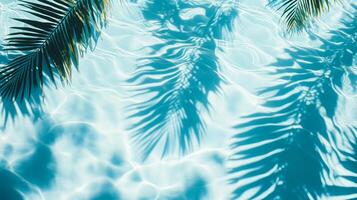 Crystal-clear aqua waves meeting shadows of broad tropical leaves on a sunlit blue pool texture photo