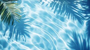 Dynamic water pool texture with soft wave ripples and overlapping tropical leaf shadows against a blue background photo