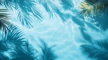 Gentle aqua waves with tropical leaves casting shadows on a bright blue background, rippling water pool texture top view photo