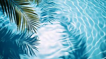 A close-up of water ripples in a pool with palm leaves' shadows creating intricate patterns on the blue surface photo