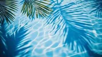 A close-up of water ripples in a pool with palm leaves' shadows creating intricate patterns on the blue surface photo