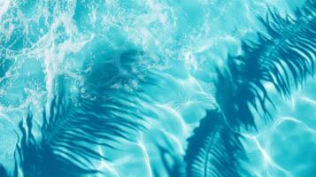 A detailed close-up of aqua waves with palm leaf shadows dancing on the surface of a bright blue pool photo