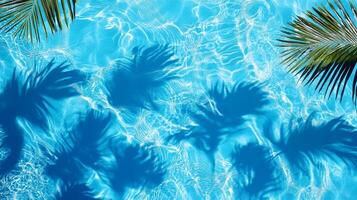 A detailed close-up of aqua waves with palm leaf shadows dancing on the surface of a bright blue pool photo