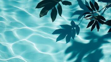 A playful combination of aqua waves and dark tropical leaf shadows contrasting against a light blue pool backdrop photo