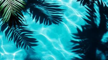 A tranquil water surface with tropical leaves casting dark shadows over bright aqua waves on a blue background photo