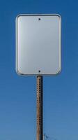 Closeup of a blank rectangular road sign on a tall post, ready for custom text photo