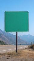 A simple green highway sign, no text, with mountains in the background, ready for custom content photo