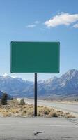 A simple green highway sign, no text, with mountains in the background, ready for custom content photo