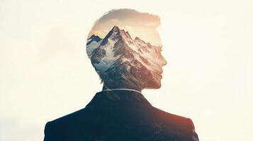 Double exposure of a businessperson looking ahead with mountain peaks subtly superimposed, symbolizing reaching new heights photo