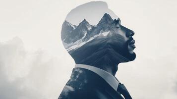 Double exposure of a businessperson looking ahead with mountain peaks subtly superimposed, symbolizing reaching new heights photo