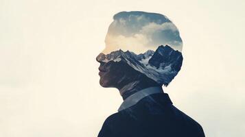 Double exposure of a businessperson looking ahead with mountain peaks subtly superimposed, symbolizing reaching new heights photo