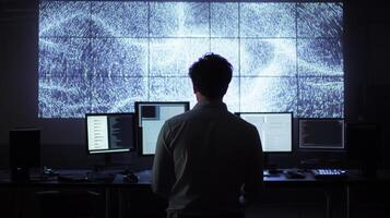 A man analyzing data on a large multi-screen setup in a dark room photo