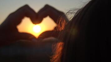 Sunset Heart Hands Silhouette - A person makes a heart shape with their hands, framing a setting sun. video