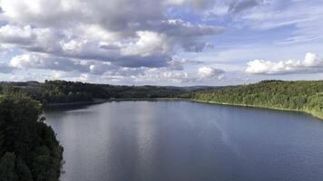 Drone flight aerial view of a lake surrounded by forest over the lake road towards the forest video