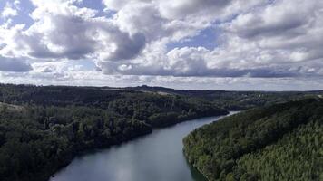 drone flight aerial view of a lake surrounded by forest moving towards a wind turbine video