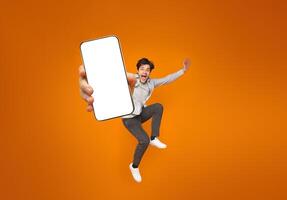 Funny man jumping with raised arms over orange studio background photo