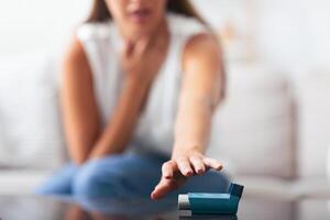 Respiratory Depression. Unrecognizable Woman Reaching For Asthma Inhaler Preventing Attack At Home. Selective Focus, Shallow Depth photo