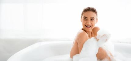 Joyful girl relaxing in bath with foam , laughing and having fun, copy space photo