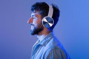 A man with a beard is wearing headphones, immersed in listening to music. He appears focused on the sound, with a serious expression on his face. photo