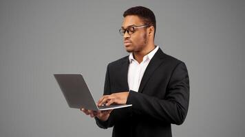 Focused African American Businessman In Glasses Using Laptop Over White Studio Background. Free space, panorama photo