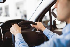 Driving Alone. Unrecognizable caucasian guy testing a car, rear view over the shoulder, selective focus on steering wheel photo
